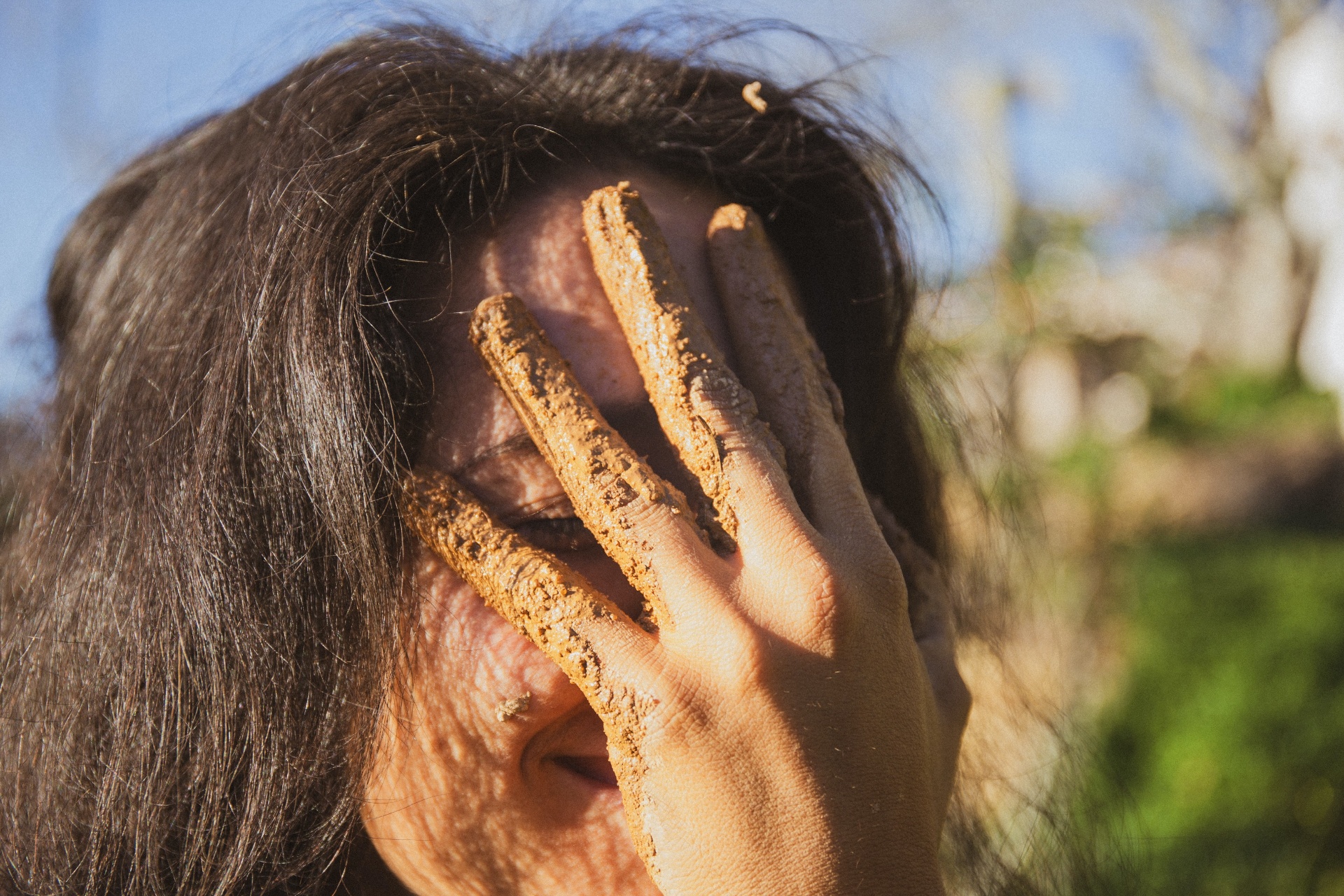 A person at Mosaic with a clay-covered hand on her face